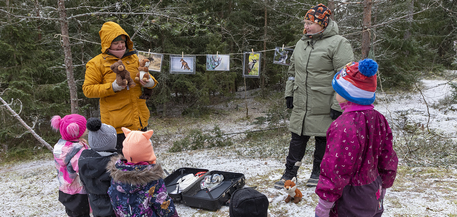 Lapset ulkoilevat metsässä lastenohjaajien kanssa.