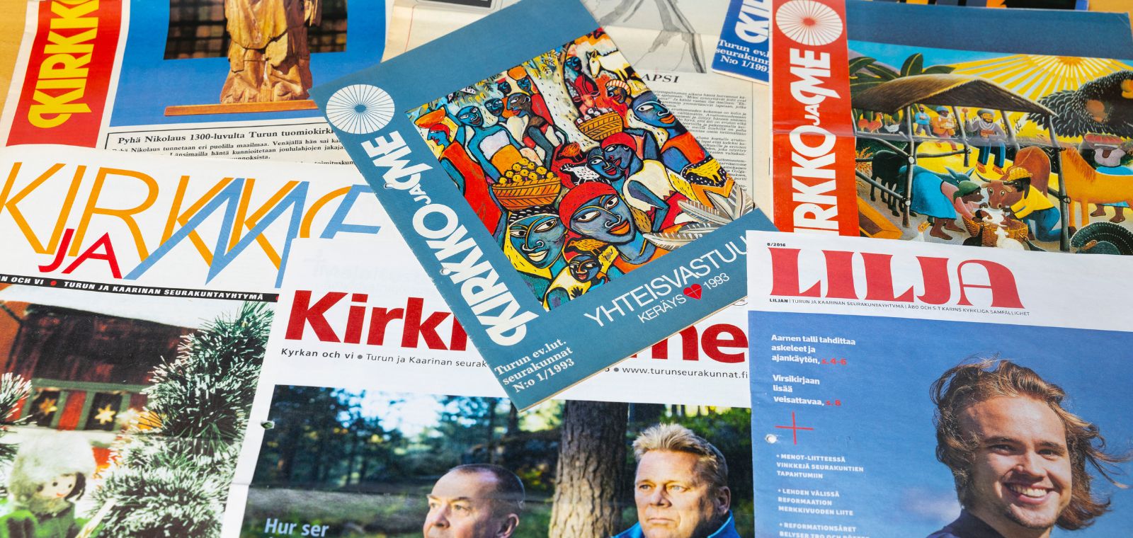 Kirkko ja me -lehtiä ja Lilja-lehtiä pöydälle aseteltuina.