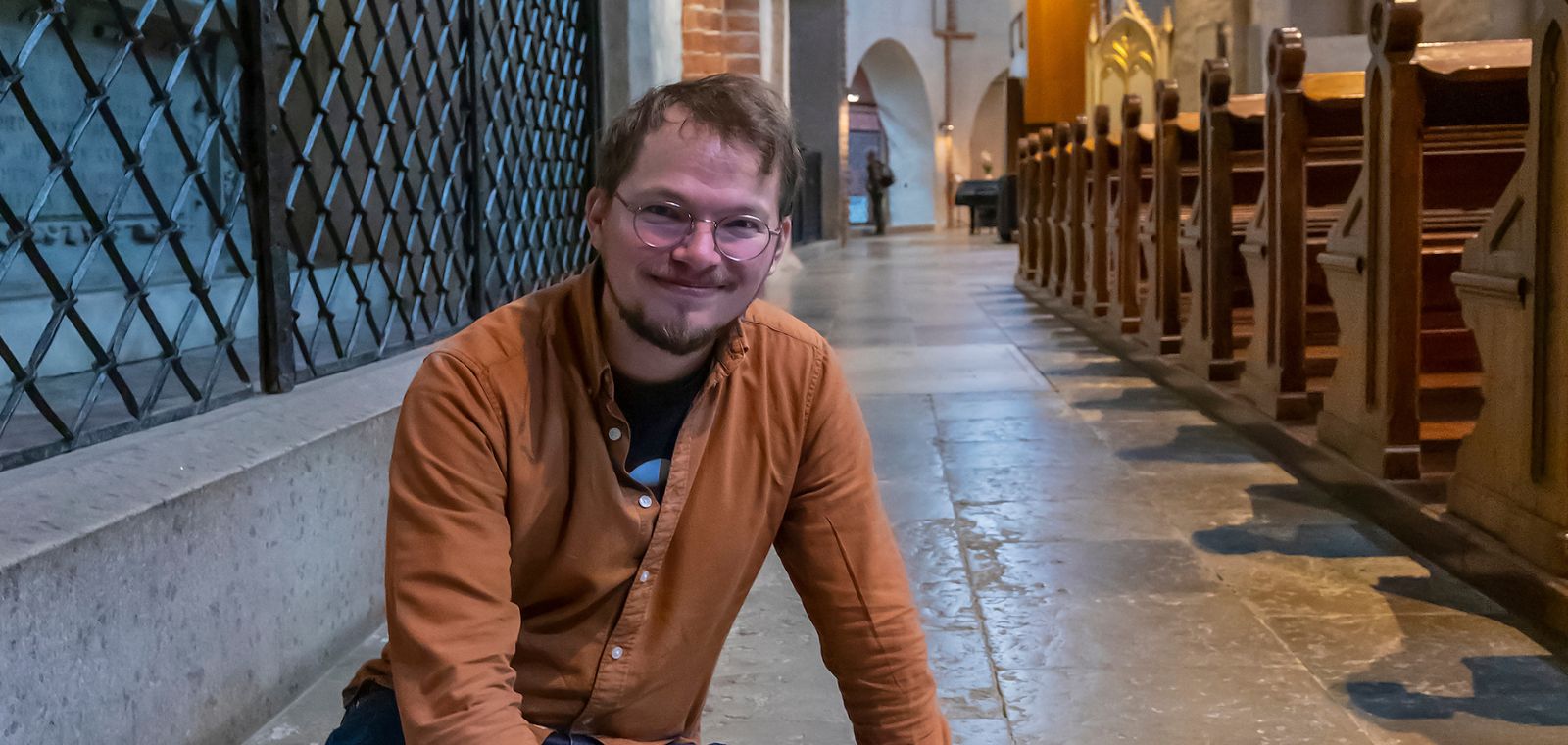 Ilari Aalto tutkii lattialla istuen Tuomiokirkon lattialaatoissa olevia fossiileita.