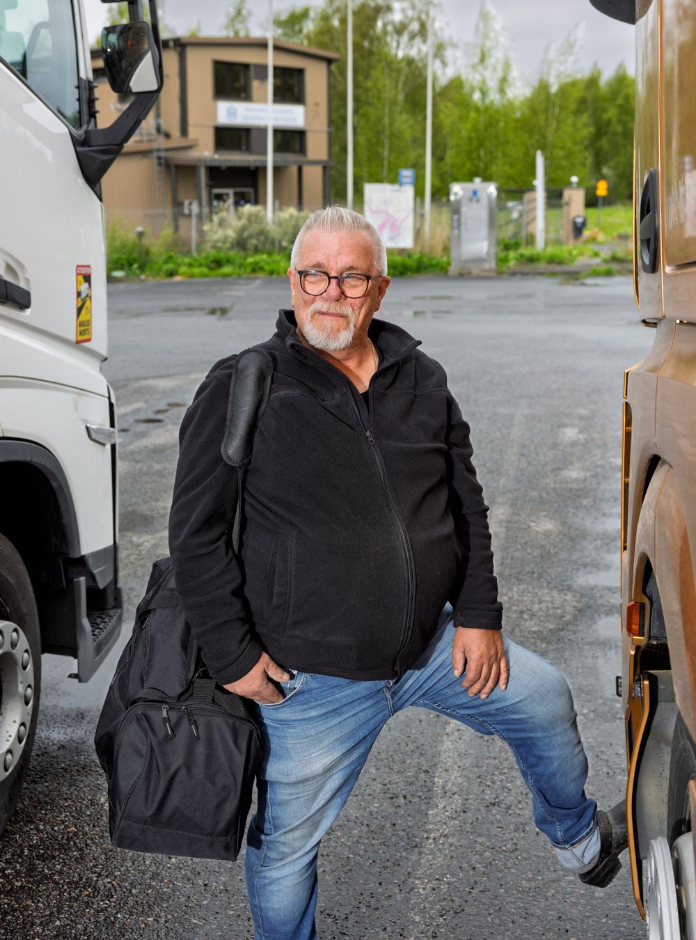 Laukkua olallaan pitävä mies kahden rekka-auton välissä, taustalla Turun Merimieskirkon rakennus
