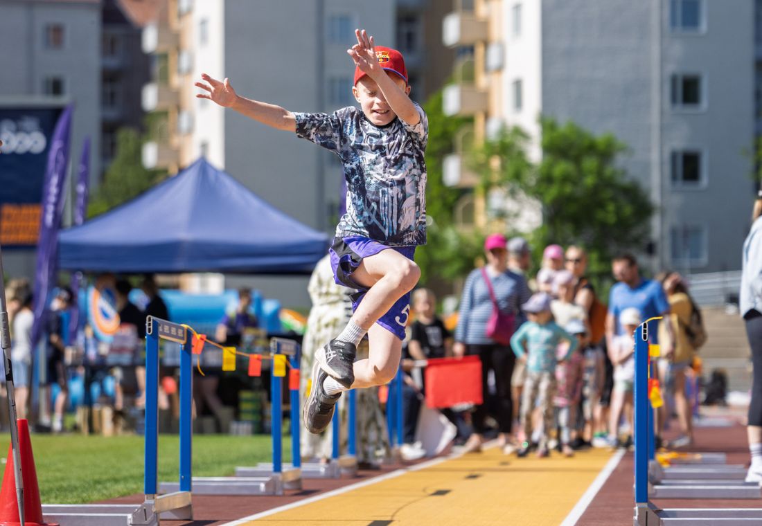 Poika hyppäämässä pituutta Paavo Nurmi -stadionilla. Taustalla vanhempia lapsineen.
