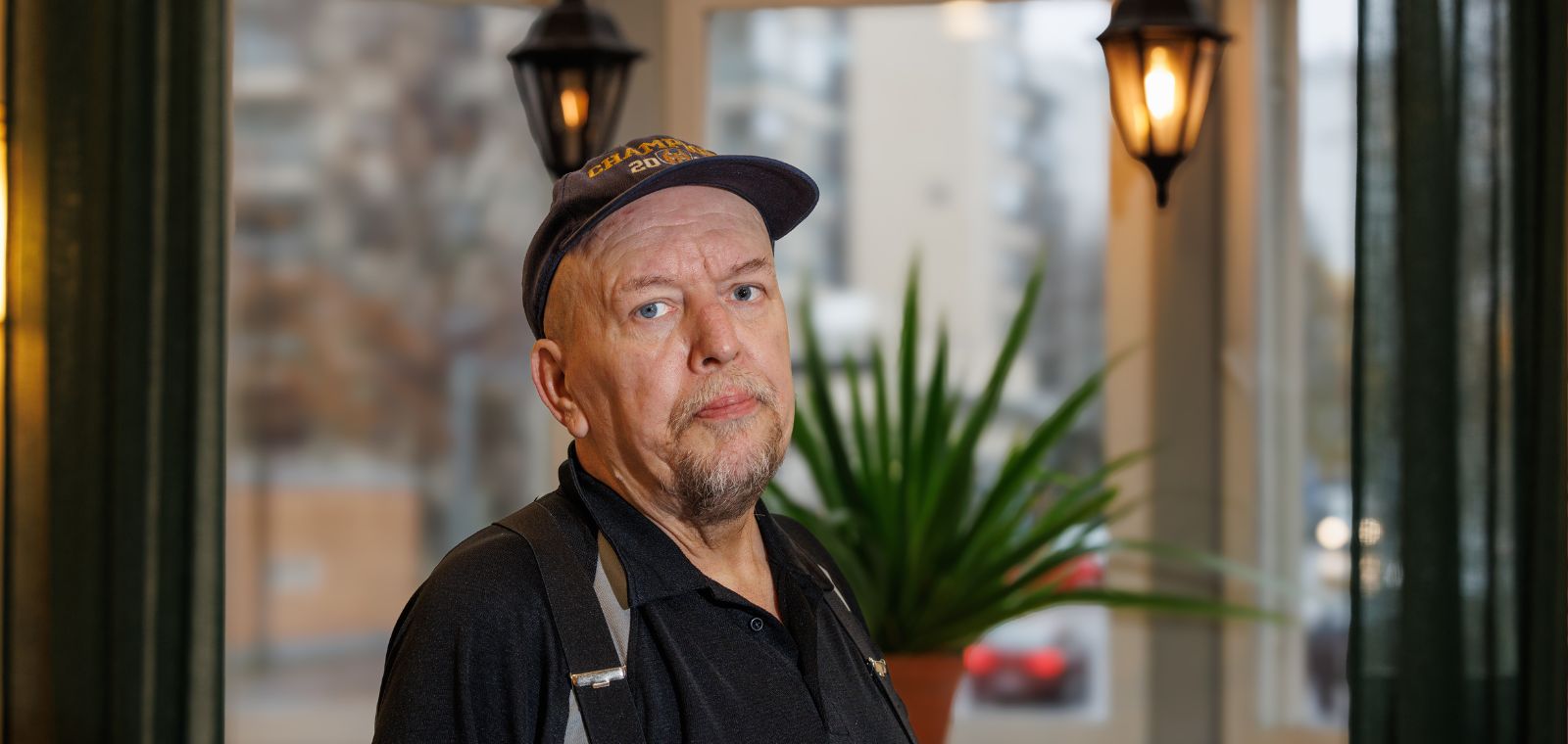 Lippalakkipäinen mies erkkerin edessä.