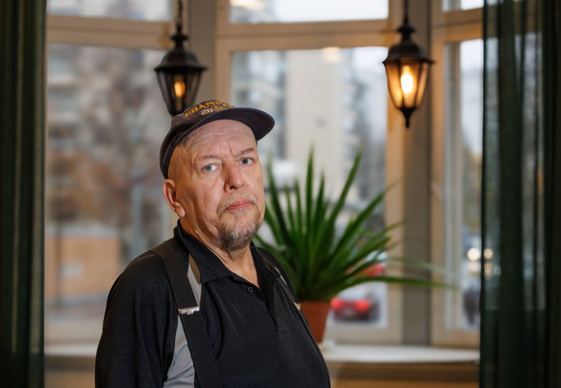 Lippalakkipäinen mies erkkerin edessä.