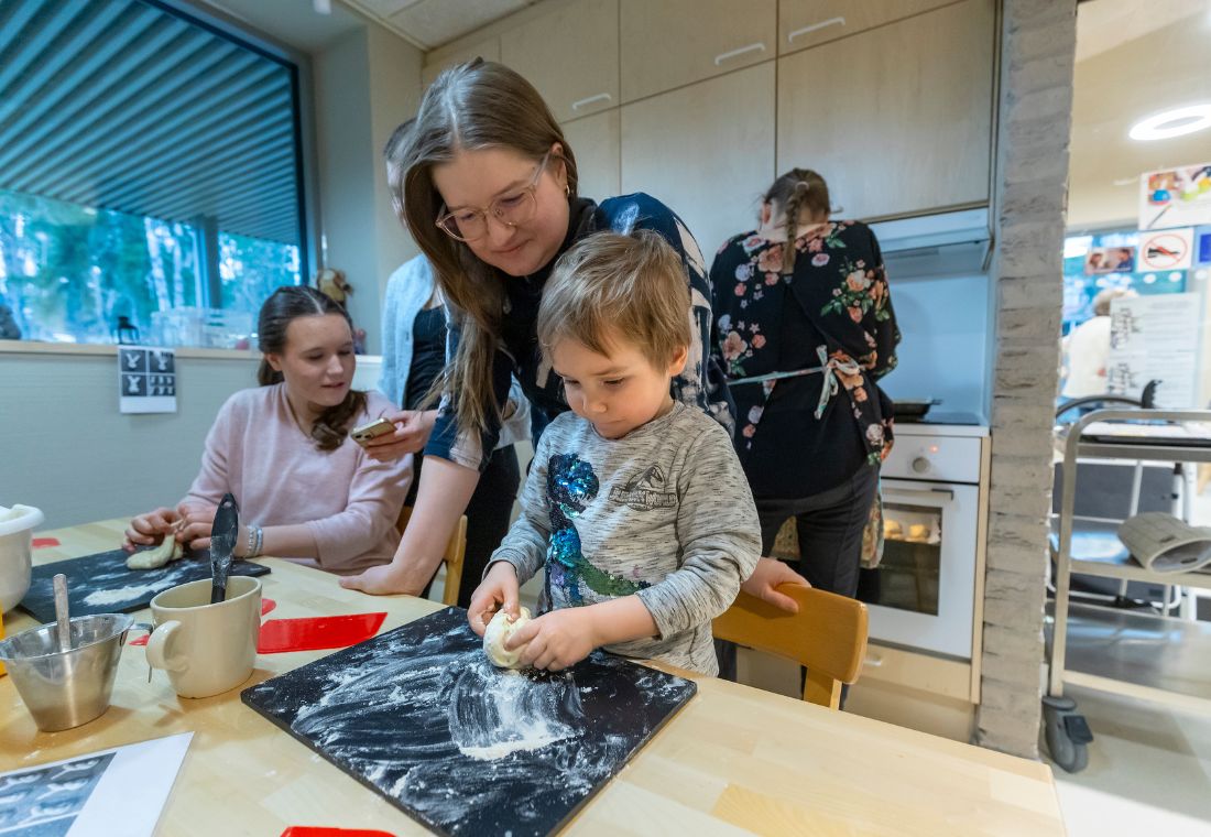 Lapsi leipoo aikuisen avustuksella.