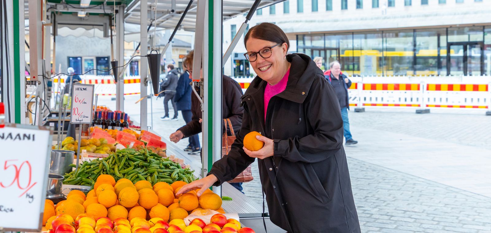 nainen valikoi appelsiineja torikojusta