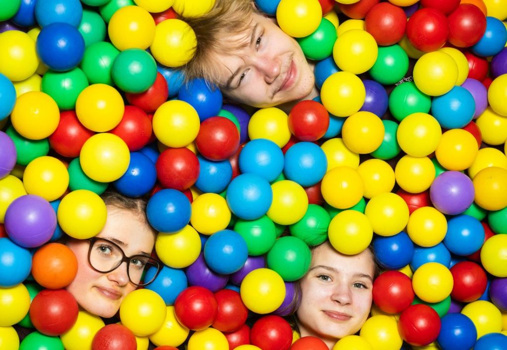 Kolme nuorta pallomeressä, vain kasvot näkyvät pallojen keskeltä.