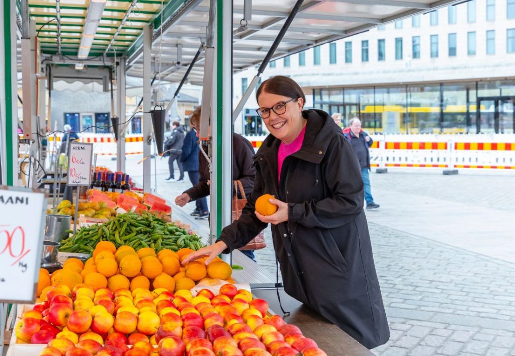 Nainen valikoi appelsiineja torikojusta.