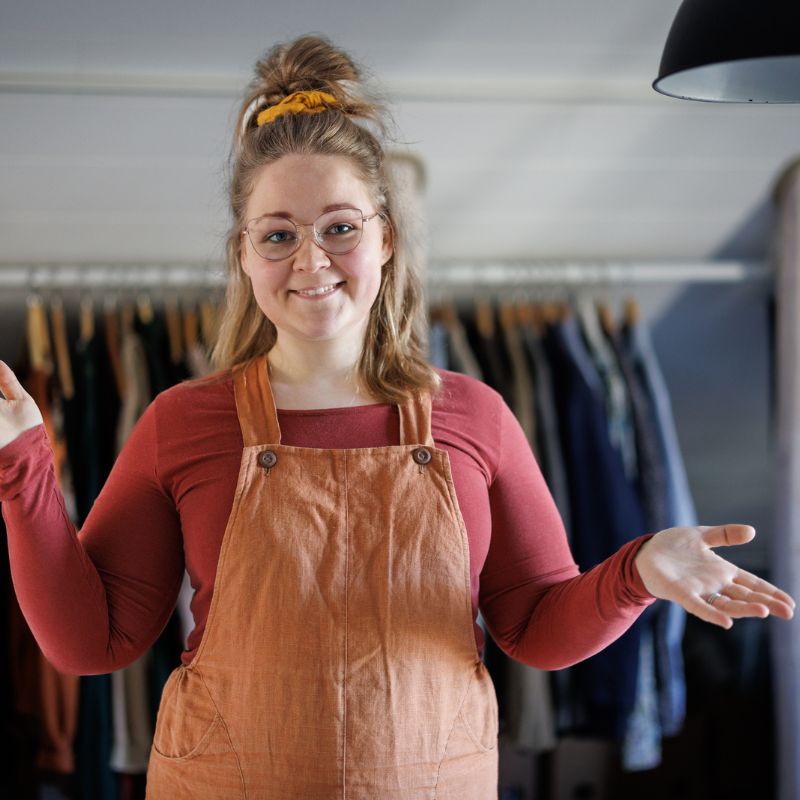 Eveliina Meriö, taustalla vinokattoisen huoneen seinustalle laitettu vaaterekki.