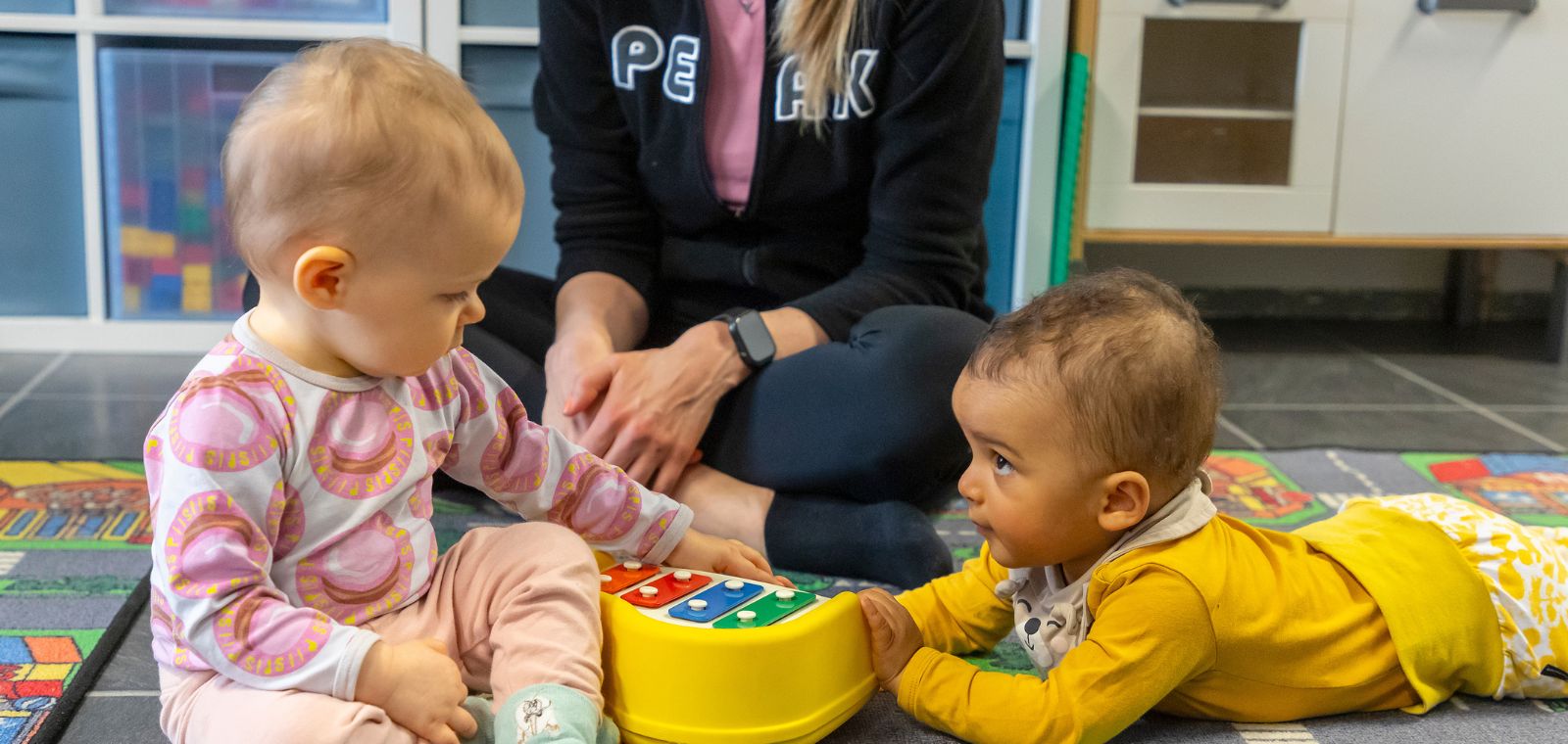 kaksi vauvaa leikkii leikkipianolla.